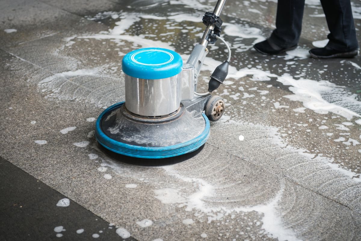 A technician operates a floor cleaning machine, ensuring a spotless finish for a professional flooring service.