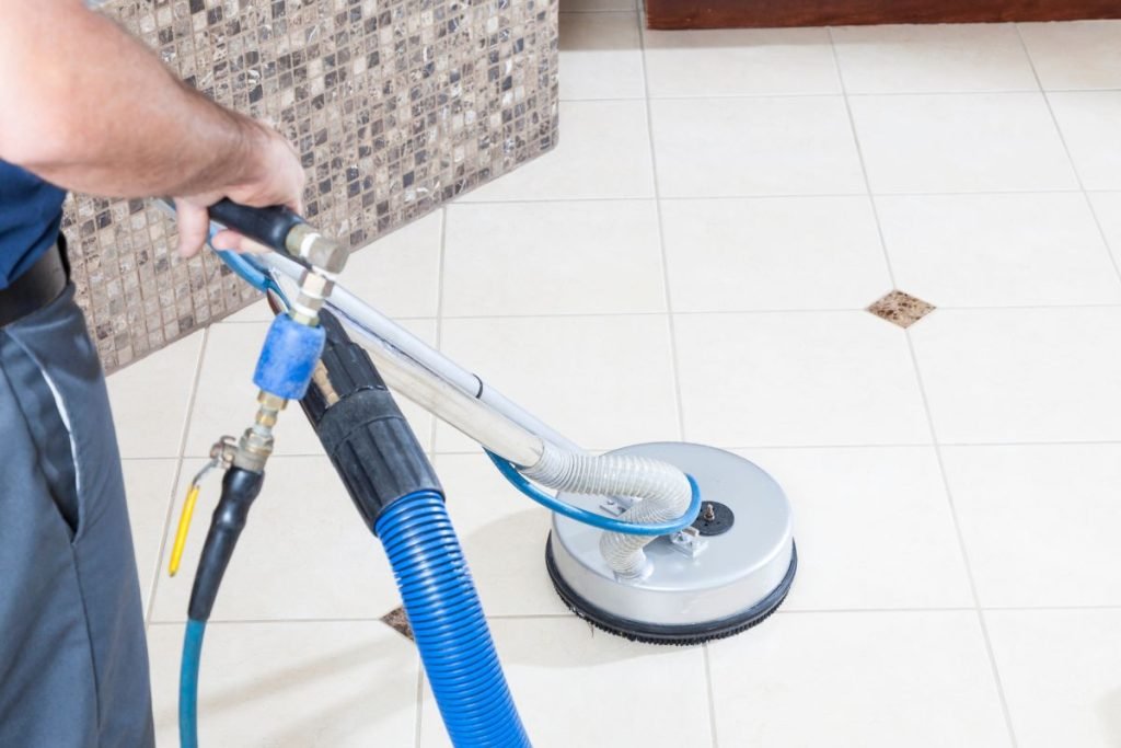 A man operates a vacuum cleaner on a tile floor, effectively removing dirt and debris from the surface.