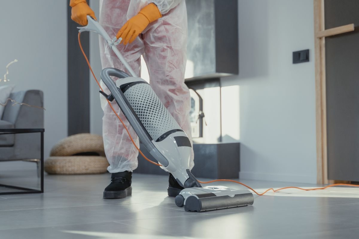 An individual wearing a protective suit is engaged in cleaning a room, emphasising safety and hygiene