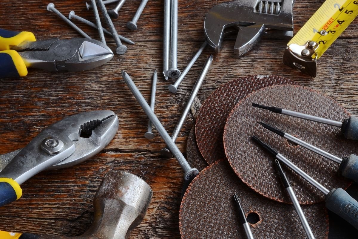 A collection of tools on a wooden table, featuring a ruler, pliers, and additional equipment for crafting or repairs.